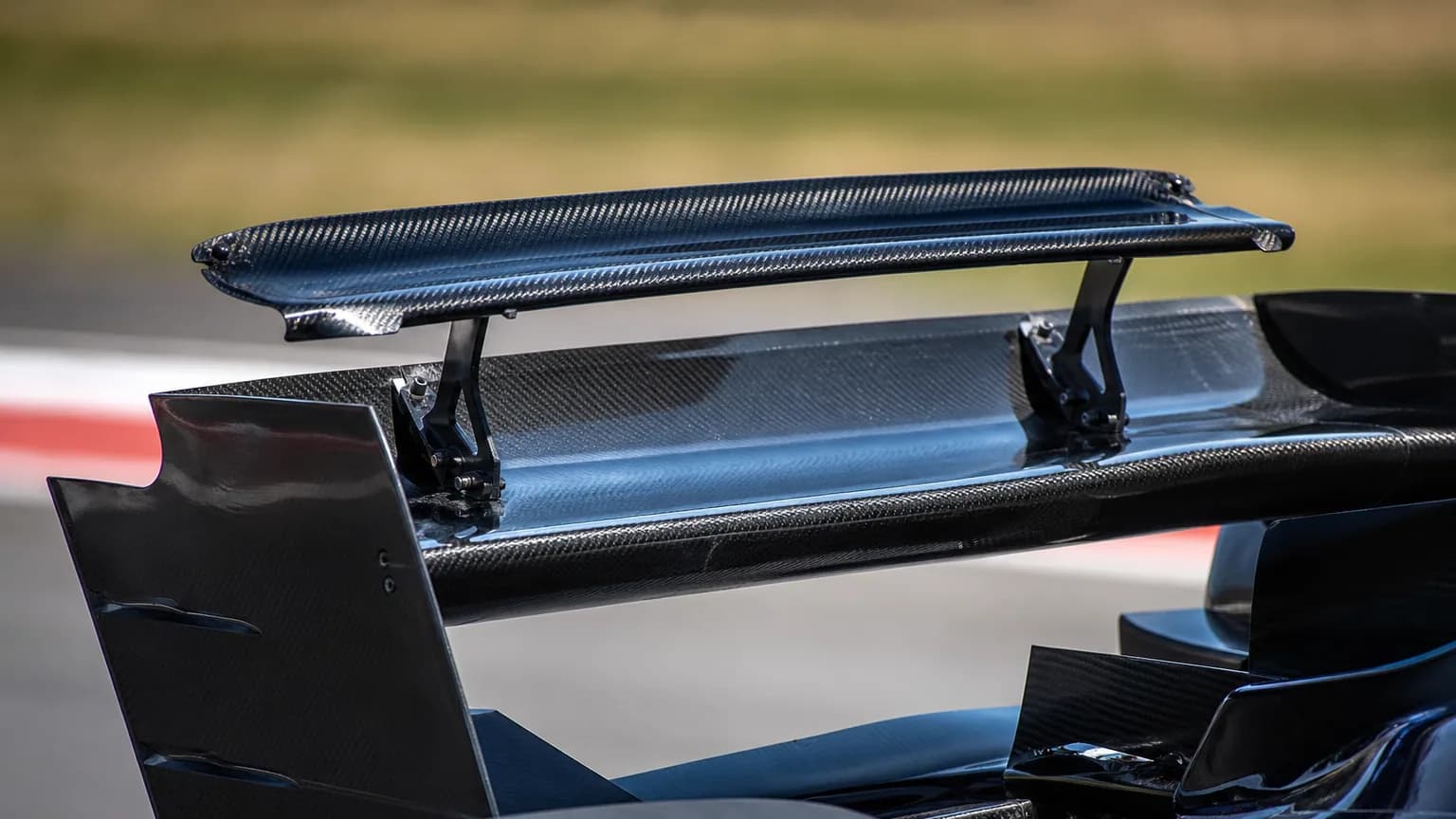 Gros plan sur l'aileron arrière d'une Formule 1 dont le volet supérieur est ouvert sur une ligne droite.